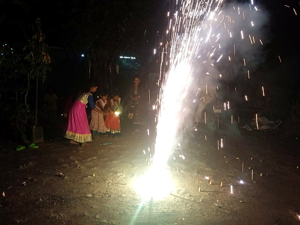 लहान मुली फुलबाजी हातात घेऊन दिवाळी साजरी करताना